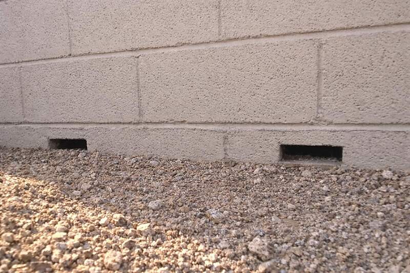 Open weep openings at the base of a painted block perimeter wall