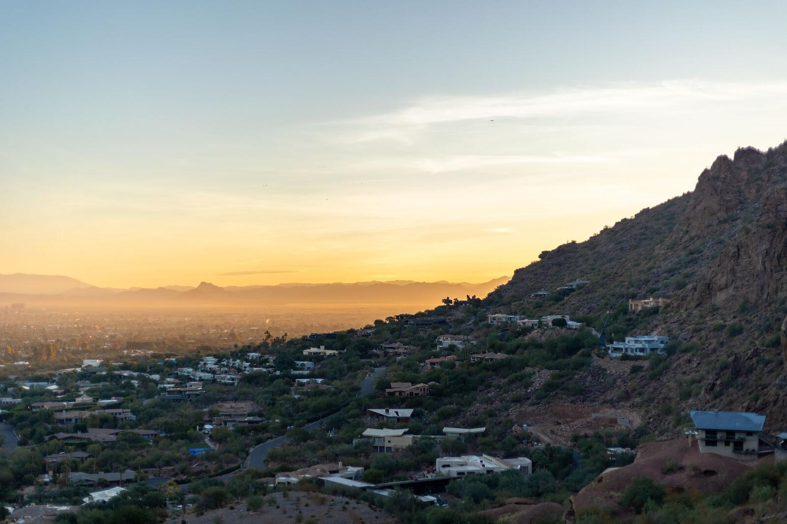 A desert mountain rising behind Phoenix rooftops at sunset