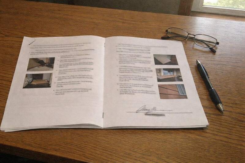 A completed multi-page inspection report open on a desk, signed and dated, with photographs printed into the pages
