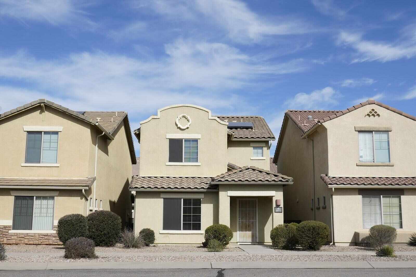 Adjacent stucco houses with concrete tile roofs on an Arizona subdivision street