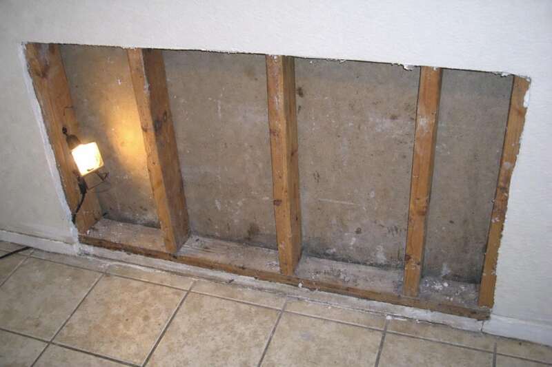 An opened section of interior wall showing the studs and the empty cavity behind